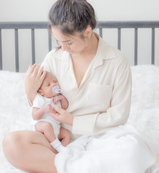 A,Beautiful,Asian,Woman,Puts,Her,Newborn,Baby,On,Her